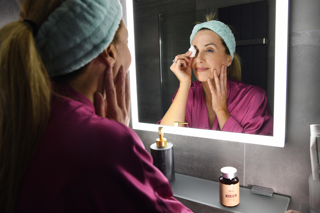 Laura doing skincare in mirror taking her skin glow supplement for skin hair and nails